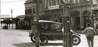 Praça da Estação da Paulista, em frente ao Campinas Hotel. Década de 1920 um Ford T estacionado para se abastecer em uma bomba de gasolina coqueiro - Atlantic. Na lateral  esquerda o início da Avenida Andrade Neves, e uma parte do prédio da Lidgerwood Manufaturings & Company Limited